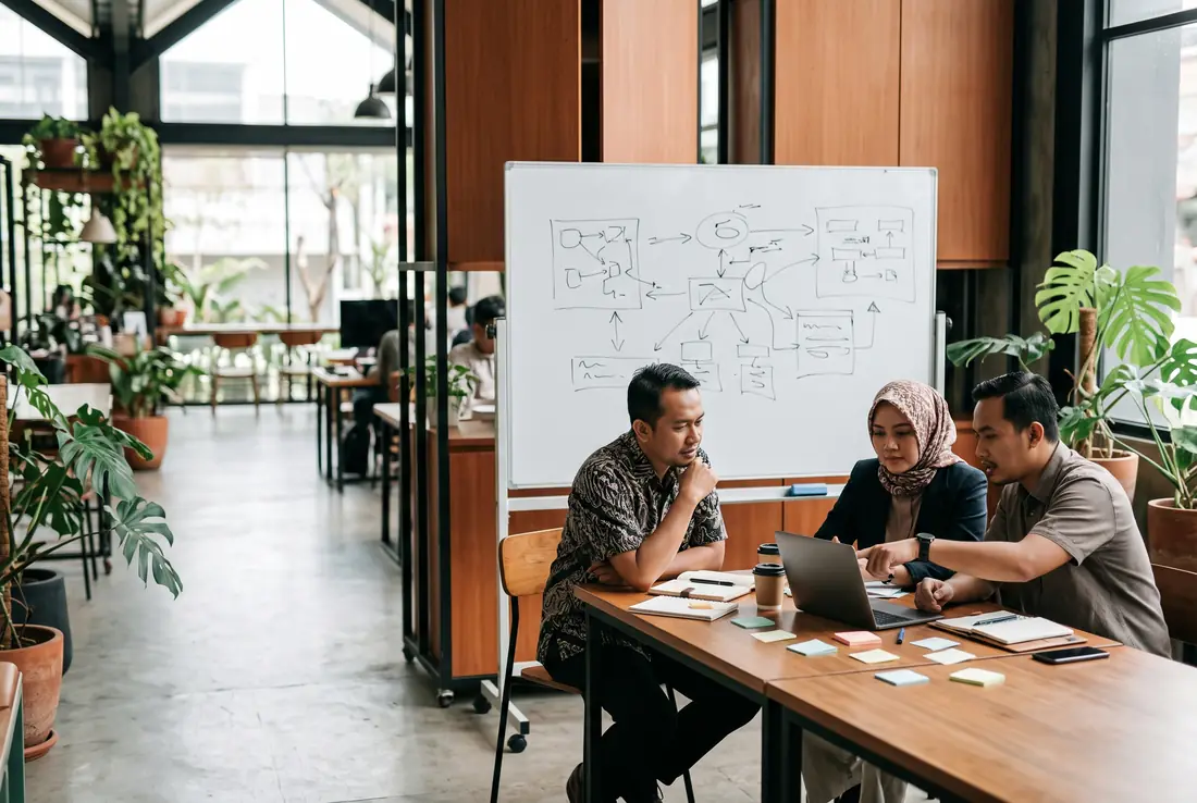 Sesi pendampingan: mentor dan dua pemilik usaha membahas rencana di laptop